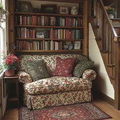 a couch sitting in front of a book shelf filled with lots of books next to a stair case