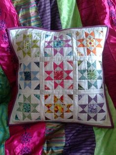 a colorful quilted pillow sitting on top of a bed