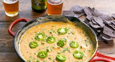 a red pan filled with cheese and green peppers next to some tortilla chips