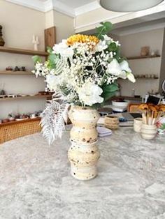 a vase filled with flowers sitting on top of a marble countertop in a kitchen