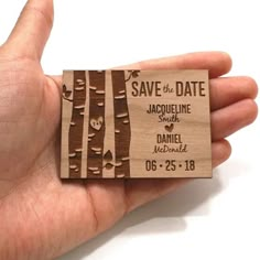 a hand holding a wooden save the date card