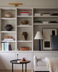 a living room filled with lots of white furniture and bookshelves on top of each other