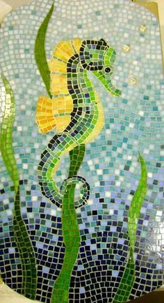 a seahorse is painted on the side of a toilet bowl with blue and green tiles