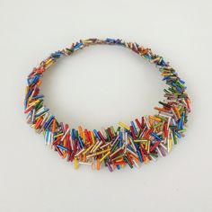 a multicolored necklace is displayed on a white surface, with small pins attached to it