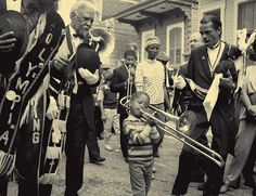 an old black and white photo of a young boy playing the trombone in front of some people