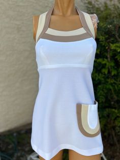 Here is a vintage 1970s white polyester tennis dress.Made by Top Seed.Following are the measurements, Bust 32", waist 28", hips 38" .Zips up the back.White in color .Tan stripe colors on top of bodice and pockets.In nice vintage condition.If you live overseas please email me before purchasing for mailing cost. Price quoted is for USA only. Please take special note of measurements. 1970s sizing was much smaller than today's standards. Tennis dresses were very short not like a regular dress. So please take special note of lengths White Retro Sleeveless Dress, White Retro Mini Dress For Summer, Retro White Mini Dress For Summer, White Vintage Cotton Mini Dress, White Sleeveless Mod Dress, White A-line Mini Dress In Mod Style, Vintage White Mini Dress For Summer, Vintage White Summer Mini Dress, White A-line Mod Dress