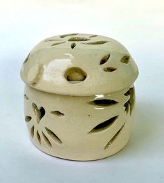 a white ceramic container with holes in the top and bottom, on a white background