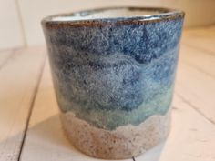 a blue and white cup sitting on top of a wooden table