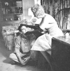 an old black and white photo of a woman sitting on the floor next to a man