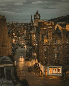 a city street at night with cars parked on the side and people walking down the road