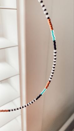 a beaded necklace hanging from the ceiling in front of a window with shutters