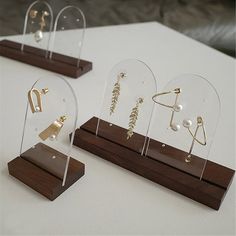 three different types of earrings on display in glass cases with wood bases and wooden base