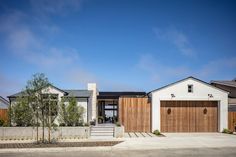 a white house with wooden garage doors on the front and side of it's home