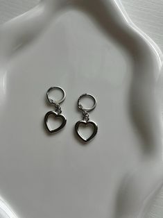 A simplistic earrings pair made with silver heart charms. Subtle enough to wear for the rainiest days, and elegant enough to dress up. Includes 1 pair of earrings (2 hoops). Sterling Silver Huggie Heart Earring, Sterling Silver Huggie Heart Single Earring, Trendy Hypoallergenic Heart Drop Earrings, Sterling Silver Single Huggie Heart Earring, Trendy Dangle Heart Earrings With Ear Wire, Trendy Heart-shaped Nickel-free Hoop Earrings, Cute Sterling Silver Hoop Earrings For Pierced Ears, Trendy Double Heart Hypoallergenic Earrings, Trendy Hypoallergenic Double Heart Earrings