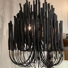 a chandelier made out of black sticks and wires hanging from it's center