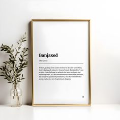 a framed poster with the words banjaxed in black on it next to a plant