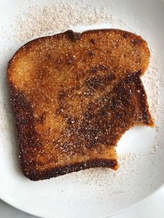 a piece of toast on a white plate with powdered sugar around it and the top half cut off