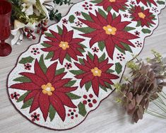 two red poinsettias on a white table runner next to a vase with flowers