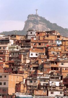 a large group of buildings in front of a mountain with a cross on it's peak