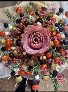 an arrangement of meats, olives and tomatoes on skewers with toothpicks