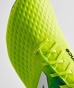 a close up view of the upper part of a soccer shoe in neon green and white