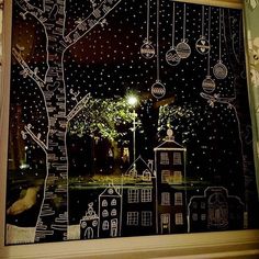 the window is decorated with white and black paper cut outs, trees, houses, and street lights