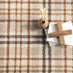 a wooden cross sitting on top of a table next to a vase and napkin holder