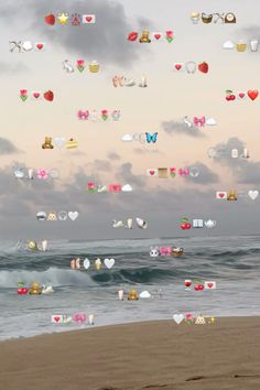 there are many hearts hanging in the air over the ocean and beach as people walk on the sand