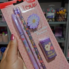 a person holding a purple pen and two other items in a package with flowers on them