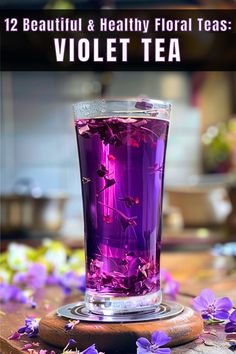 a glass filled with purple tea sitting on top of a wooden table