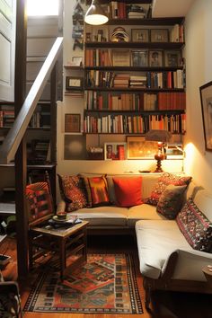 a living room filled with furniture and bookshelves next to a stair case full of books