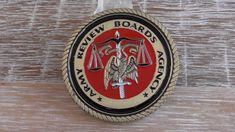 a red and black badge with an eagle on it's side sitting on top of a wooden table