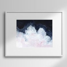 a painting hanging on the wall next to a white frame with a black background and pink clouds