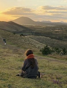 a woman sitting on top of a lush green hillside