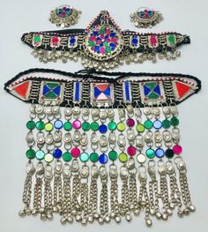 * This is a complete Afghan Kuchi set including a choker, Matha Patti, and hoops. Each piece exhibits multicolor glass stone inlay, use of solid metal alloy, beads, bells, and motifs. The metallic weaving technique is used in the making of the choker and mathapatti while the earrings are made in chandballi style. * The traditional Afghan Kuchi jewelry is known for its variety and use of several materials such as colorful glass jewels, coins, bells, dangles, beadwork, embroidery, mirrors, laces, Traditional Multicolor Jewelry For Traditional Ceremonies, Traditional Multicolor Jewelry For Ceremonies, Multicolor Bohemian Jewelry For Traditional Ceremonies, Bohemian Jewelry For Ceremonial Festival, Bohemian Festival Jewelry For Ceremonial Occasions, Traditional Multicolor Jewelry With Traditional Patterns, Festive Beaded Bohemian Jewelry, Bohemian Multicolor Jewelry For Navratri, Bohemian Jewelry With Motifs For Festivals