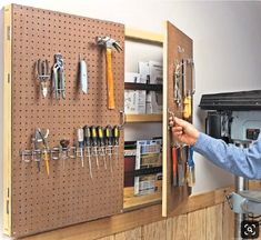 a man is working on a wall mounted tool rack with pegs and wrenches