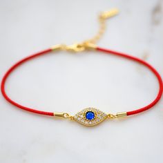 "The tradition of red string bracelets dates back many hundreds of years. The red color is meant to symbolize Protection and Good Luck. Paired with a beautifully crafted evil eye, this bracelet is sure to bring good vibes and protection to its owner ✨ ➤Details➤ ▪︎ Made of 925 Sterling Silver ▪︎ Plated in 14k Gold or Rhodium ▪︎ Durable, High Quality Red String ▪︎ Measures 6.75\" + 1.5\" Extension Chain ▪︎ Lobster Clasp Closure ▪︎ Evil Eye Charm features a vibrant, sapphire cz stone in the center Red Spiritual Bracelet For Good Luck, Spiritual Red Bracelet For Good Luck, Adjustable Red Bracelet For Blessing, Red Spiritual Bracelets For Friendship, Adjustable Red Jewelry For Festivals, Elegant Red Bracelets For Good Luck, Gold Jewelry For Friendship Festivals, Red Bangle Jewelry For Friendship, Red Bangle For Friendship