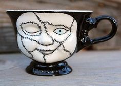 a black and white cup with a face painted on it