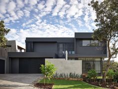 a modern house with trees and grass in the front yard