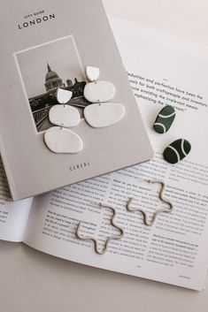 the book is open to show some white and green brooches on top of it