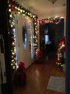 a hallway decorated for christmas with lights and wreaths on the door, along with other decorations