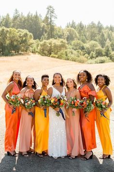 a group of women standing next to each other holding bouquets in their hands and smiling at the camera