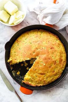 a skillet with a cake in it on top of a table next to plates and utensils