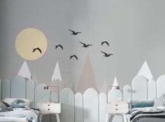 a bedroom with two beds and birds flying over the top of the mountains on the wall