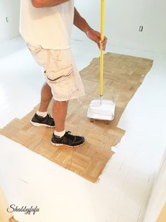 a man standing on top of a wooden floor with a mop in his hand