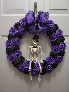 a wreath decorated with purple roses and a skeleton wearing a top hat is hanging on the front door