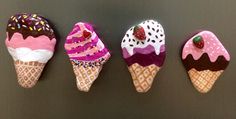 five ice cream cones are lined up in a row on a black surface and one is decorated with sprinkles