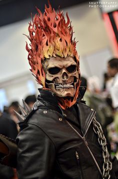 a man wearing a skull mask with flames on his head and chain around his neck