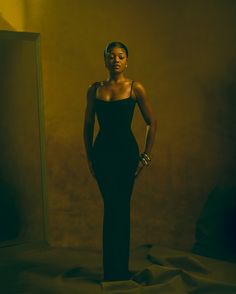 a woman standing in front of a mirror with her hands on her hips wearing a black dress