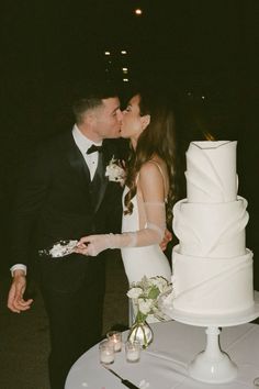 a bride and groom kissing in front of a wedding cake